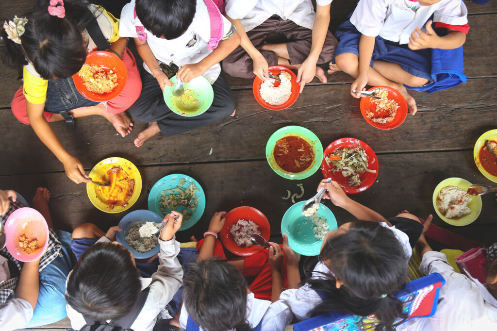 Image of School Children eating lunch together on the floor.